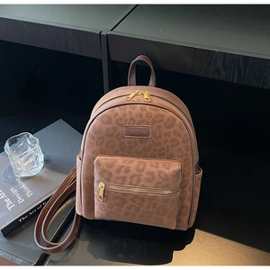 Detail of leopard print travel backpack with gold metal zipper and branded metal plate