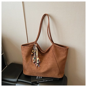 Gros plan d'un sac cabas en daim marron avec rivets dorés et pampille à perles colorée
