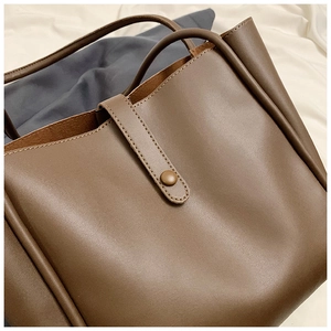 Détail d'un sac cabas en similicuir marron avec texture lisse et bride à bouton-pression