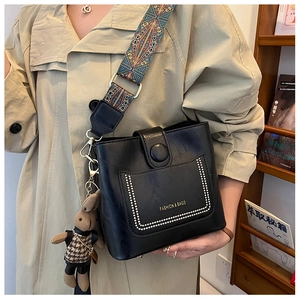 Detail of black leather bucket bag with ethnic strap and plush rabbit charm