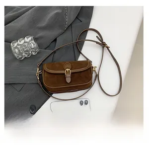 Macro detail of brown suede and smooth leather stitching on a retro saddle bag clasp