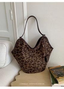Détail du sac cabas en daim léopard avec bordure en cuir marron et breloque en cœur