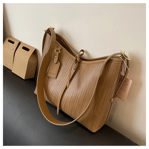 Dettaglio borsa tote intrecciata marrone con tracolla in pelle e targhetta logo