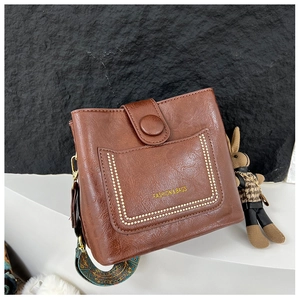 Detail of brown litchi pattern leather bucket bag with vintage printed wide strap