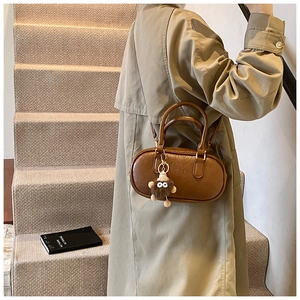 Détail du sac cylindre en cuir marron foncé avec logo ATN et breloque en peluche