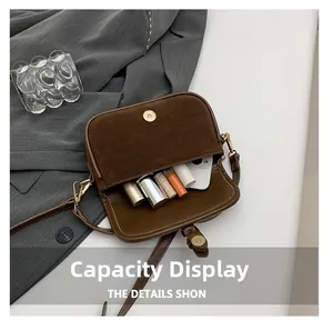 Detail view showing internal capacity for phone and lipsticks in brown leather crossbody bag