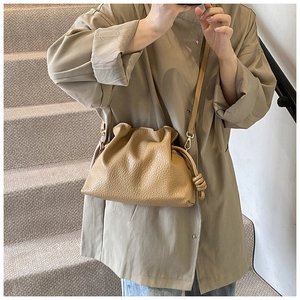 Khaki pleated cloud bucket bag in lychee pattern faux leather worn by model on stairs