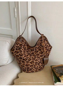 Détail du sac hobo en daim léopard avec bordure en cuir marron et pendentif en cœur