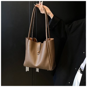 Détails d'un sac cabas en cuir marron rétro porté par un mannequin en costume noir