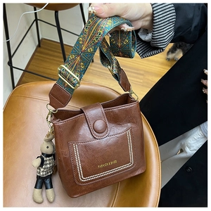 Detail of vintage brown bucket bag with ethnic embroidery strap and cute bunny charm