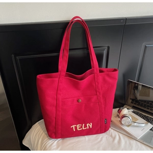 Détail du grand sac fourre-tout rouge en toile avec lettres brodées et poche extérieure