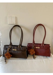Detailed close-up of retro brown tote bag with metal twist lock and cute plush bear charm