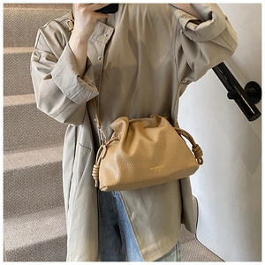 Detail view of a brown pleated bucket bag with knot accents on a shoulder strap