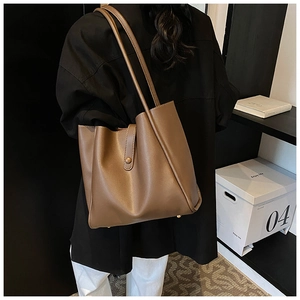 Grand sac cabas en cuir marron montrant la texture mate et les clous de protection en métal