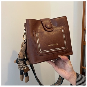 Detail of dark brown bucket bag featuring fine leather texture and rabbit charm