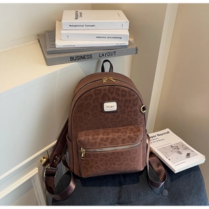 Detailed close-up of brown leopard print backpack with brand logo and gold zipper detail
