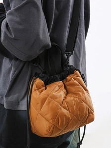 Brown quilted nylon bucket bag with drawstring closure and crossbody strap on model