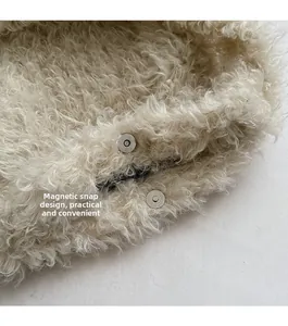 Detail of the magnetic buckle closure on a beige plush faux fur crossbody tote bag
