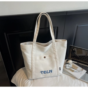 Détail du sac cabas en toile avec logo brodé et poche avant pour les étudiants
