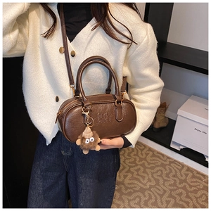 Detail of vintage brown leather bowling bag with ATN embossed logo and cute plush charm