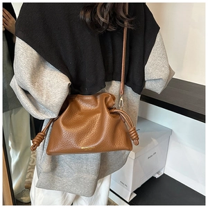Detailed view of brown leather bucket bag with pleated drawstring closure and gold logo