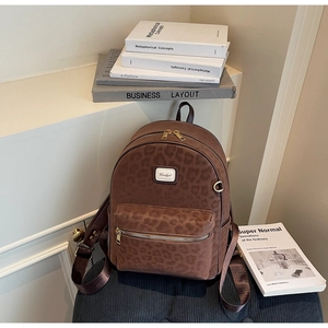 Detailed close-up of brown leopard print backpack with gold zippers and matte texture
