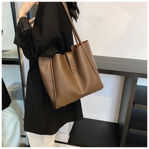 Vue latérale du grand sac cabas en cuir marron foncé avec coutures verticales porté par mannequin