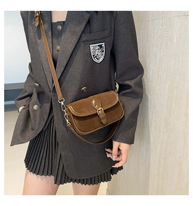 Detail view of retro brown faux suede crossbody bag with gold hardware and flap closure