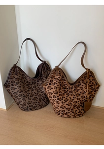 Détail de cabas en daim imprimé léopard avec bordure en cuir et breloque cœur tons marron
