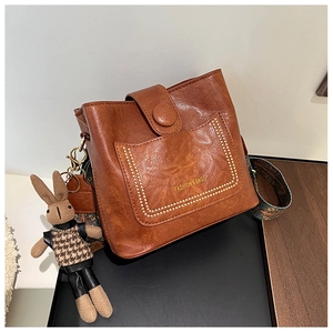 Detail of vintage brown bucket bag with ethnic strap and rabbit charm accessory
