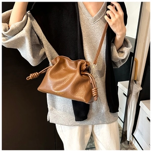 Detail of caramel leather bucket bag with drawstring closure and fine pebble grain texture