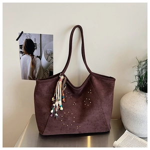 Détail d'un grand sac cabas en daim bordeaux avec clous dorés et pompons colorés