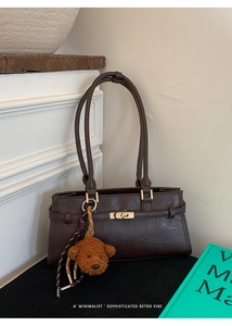 Close-up of retro brown tote bag with metal twist lock and cute plush bear charm