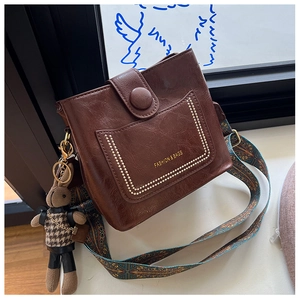 Detail view of vintage dark brown bucket bag with pearl chain trim and animal charm