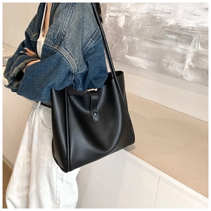 Détail d'un grand sac cabas noir en cuir porté à l'épaule pour un style professionnel