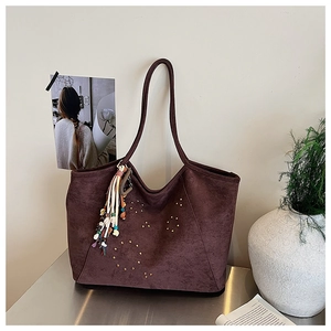 Détail du sac cabas en suédine marron foncé avec rivets dorés et breloque ethnique