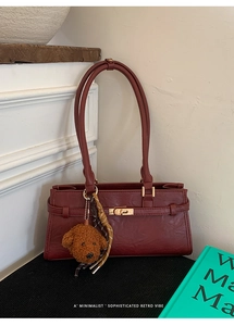 Detail of dark red retro tote bag featuring a gold twist lock and a cute teddy charm