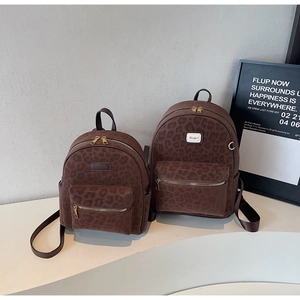 Detail of two brown leopard print backpacks in different sizes on a modern display stand