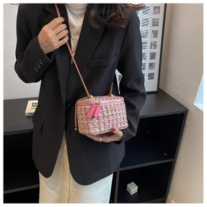 Dettaglio mini borsa a secchiello in tweed rosa e bianco con catena d'oro su modella