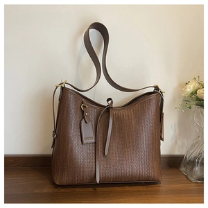 Dettaglio della borsa tote marrone intrecciata con texture a V e tracolla coordinata