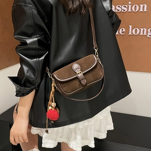 Close-up of vintage brown suede shoulder bag with strap buckle and plush charm detail