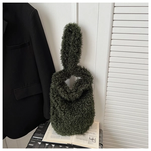 Detail of dark green shearling knot bag showing soft plush texture on a fashion book