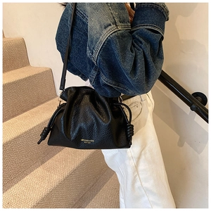 Detail of black drawstring bucket bag with litchi texture and elegant side knots