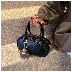 Détail du sac Boston noir avec lettres ATN embossées et breloque en peluche marron