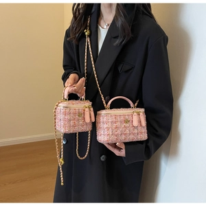 Detail of pink tweed vanity bags with golden camellia accents and leather chain handles