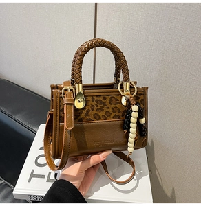 Détail du sac à main léopard marron avec poignée tressée et breloque en perles