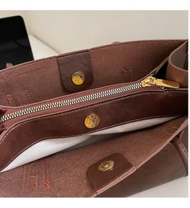 Close-up of leather tote interior with gold zippers, magnetic snaps and herringbone lining