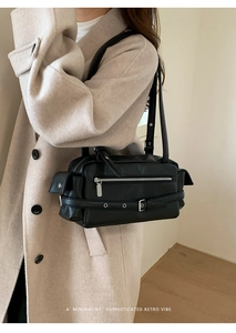 Close-up of a black retro leather shoulder bag with metallic buckle and zipper details
