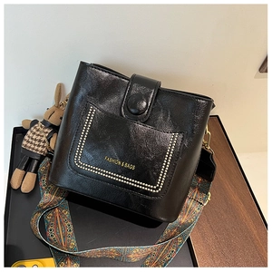 Detail of vintage black bucket bag with gold rivets and ethnic style wide strap