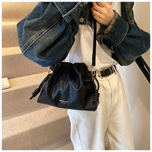 Fashionable black leather bucket bag with gold lettering shown in a stylish lifestyle setting